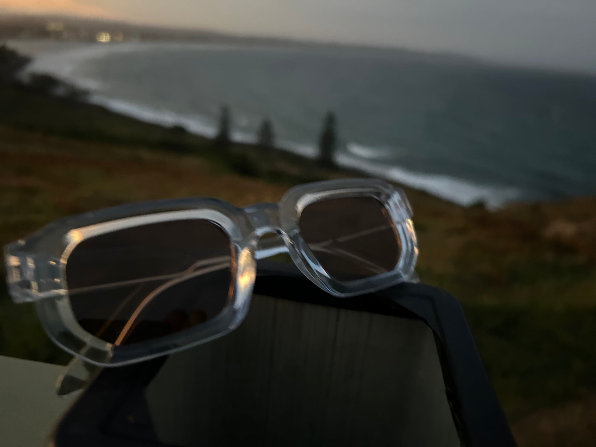 Sunglasses with a scenic background of a beach and sunset.